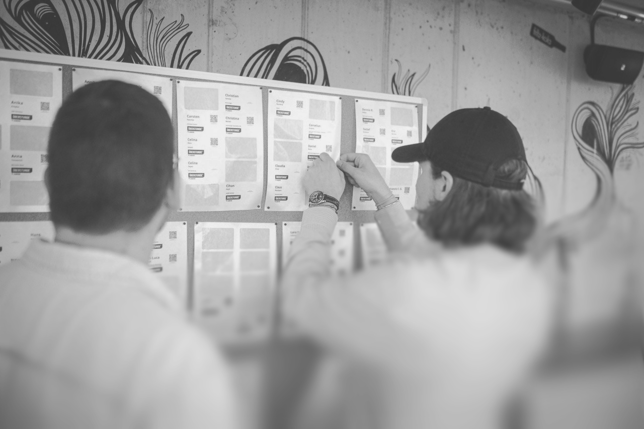 Zwei Personen heften Namensschilder an eine namensschild.io-Wand auf einem Event